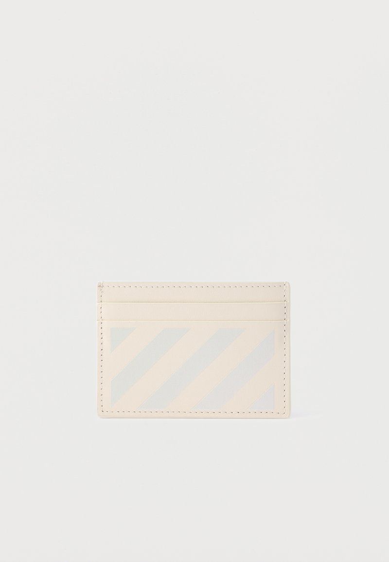 Κρεμ θήκη καρτών με τέσσερις υποδοχές για κάρτες και διακριτικό διαγώνιο ριγέ σχέδιο στην μπροστινή τσέπη, τοποθετημένη σε λευκό φόντο.