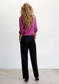 Fuchsia bluse med oprullede ærmer parret med sorte, skræddersyede bukser. Glat stof og løs pasform, sko med smalle hæle.