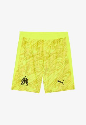 Shorts sportivi gialli con un motivo a vortice testurizzato, con loghi neri di una squadra sportiva e di un marchio sui lati sinistro e destro, rispettivamente.