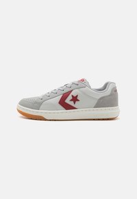 Sneaker din piele gri și velur cu accente roșii. Dispune de o talpă albă, vârf rotund și un design clasic cu șireturi. Talpă din cauciuc pentru tracțiune.