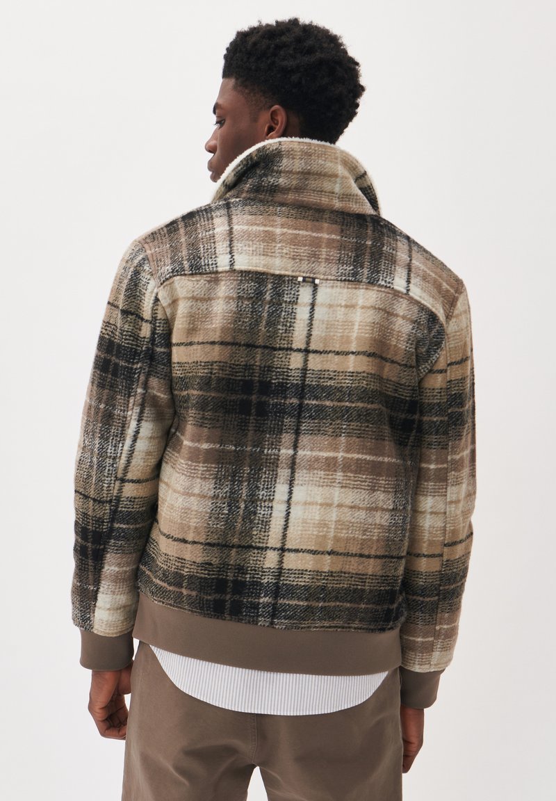 Karo-Jacke mit hohem Kragen, aus strukturiertem Stoff in Braun, Beige und Schwarz. Gerippte Bündchen und Saum. Auffälliges Karomuster.