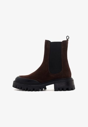 Bottines en suede marron avec des panneaux latéraux élastiques noirs, une semelle en caoutchouc texturée et une languette pour un enfilage plus facile. Design à plateforme épaisse.