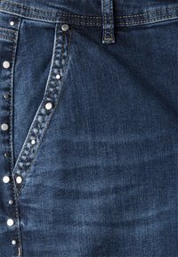 Denimkjol med mörk tvätt och silvernitar längs sid sömmen, kontrasterande sömmar och en figurnära design. Slät textur.