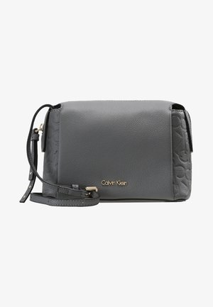 Grijze Calvin Klein crossbodytas van gekorreld leer met verstelbare riem en subtiel blindgeperst logo aan de zijkant.