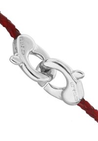 Fermoir en métal argenté reliant un cuir rouge tressé. Le fermoir a des bords lisses et arrondis avec des détails gravés sur un côté.