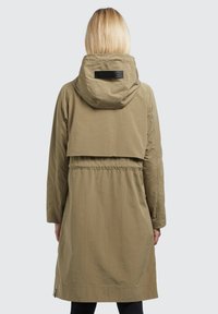 Parka leggera color khaki con cappuccio, vita cintrata e dettaglio di ventilazione nella parte posteriore. Texture liscia, design minimalista e una patch del marchio sul colletto.