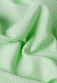 Tessuto verde chiaro con una morbida texture, caratterizzato da sottili righine e pieghe che creano profondità e dimensione. Ideale per abbigliamento informale.