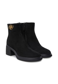 Stivaletti neri in suede alla caviglia con tacco a blocco, chiusura con zip e un emblema decorativo dorato. Texture liscia con un design elegante e moderno.