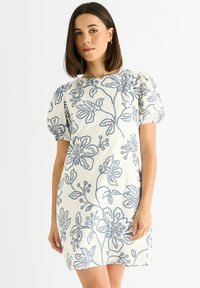 Short white dress with blue floral embroidery, puff sleeves, and a straight cut. Features a round neckline and soft texture.