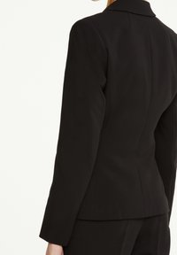 Černý přizpůsobený blazer s klasickým límcem, strukturovanou siluetou a hladkým povrchem, zobrazený ze zadní strany. Žádné viditelné vzory ani akcenty.