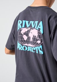 Dunkelgraues Baumwoll-T-Shirt mit einer großen Globus-Grafik in Pink und Blau, darüber und darunter der Text "RIVIA PROJECTS".
