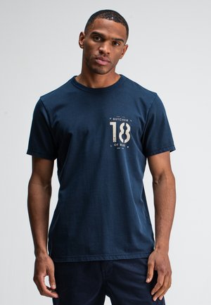 Navy blue cotton t-shirt with a round neckline, short sleeves, and a printed graphic featuring "BUTCHER 18 of BLUE" on the front.