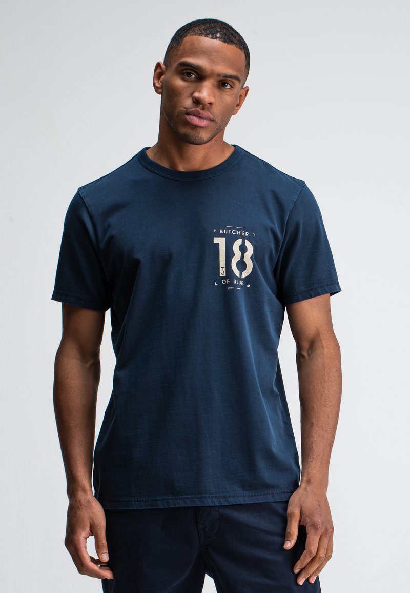 Navy blauwe katoenen t-shirt met een ronde halslijn, korte mouwen en een bedrukte graphic met "BUTCHER 18 of BLUE" op de voorkant.