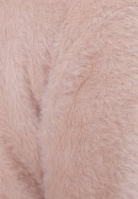 Rosa fluffig tyg med en mjuk, texturerad yta och synliga fina fibrer, vilket ger en varm och inbjudande look.