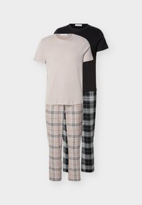 Δύο σετ βαμβακερές πιτζάμες: ένα μπλουζάκι μπεζ με παντελόνι μπεζ καρό, ένα μαύρο μπλουζάκι με παντελόνι καρό σε μαύρο και άσπρο, εκτεθειμένα σε απλό φόντο.