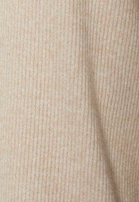 Tessuto a maglia color beige chiaro con fine ribbing. Texture morbida con una leggera lucentezza, che offre un aspetto accogliente e una leggera elasticità.