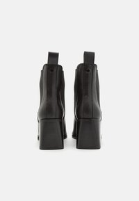 Botines de tacón negro con cuero suave, paneles elásticos en los laterales y tacón cuadrado. Lengüeta trasera para un fácil uso.