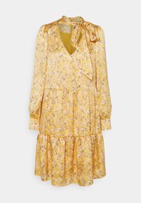 Robe longue jaune à fleurs avec plis, col en V, jupe à étages et détail d'un nœud noué au niveau de l'encolure.