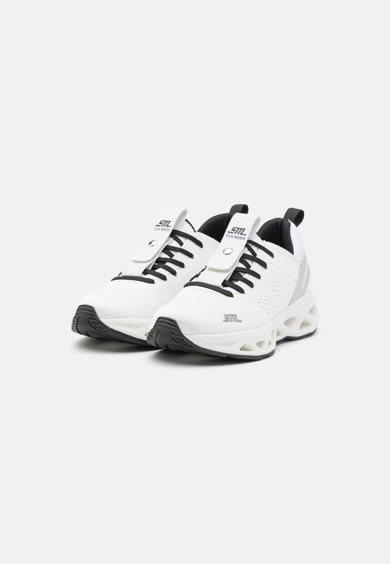 Scarpe atletiche bianche realizzate in rete con un design testurizzato, stringhe nere e una suola spessa e a contrasto. Presentano un logo e una linguetta.