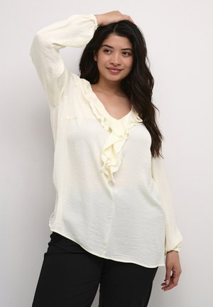 Blusa giallo chiaro con scollo a V arricciato, maniche lunghe con polsini elasticizzati e vestibilità rilassata. Tessuto morbido e texturizzato con orlo curvo.