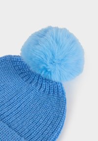 Beanie lavorato a maglia blu con un grande pompon morbido di un azzurro chiaro sulla parte superiore, caratterizzato da costine testurizzate su tutto il corpo principale.