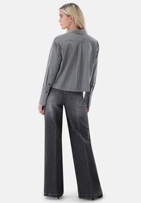 Cropped black and white gingham shirt with long sleeves, paired with high-waisted, wide-leg gray denim jeans featuring visible stitching.