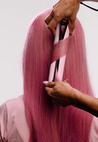 Raktång med svart och rosa design som lockar långt, rakt, pastellrosa hår. Slät textur; hand placerad för styling.