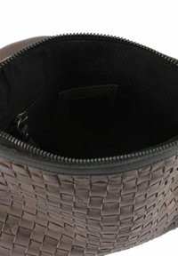 Bruine gevlochten leren tas met een ritssluiting aan de bovenkant, met een donker interieur en een subtiele textuur. Inclusief een klein zakje aan de binnenkant.