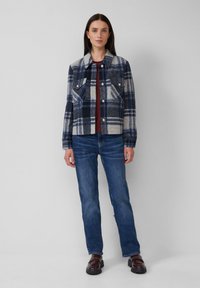 Ruitenjasje in een navy en grijze wolmix met borstzakken, zilveren knopen, gecombineerd met blauwe jeans en bruine schoenen. Soepele, gestructureerde vormgeving.