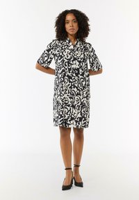 Kurzes Kleid mit Kurzärmeln im schwarz-weißen Blumenmuster, mit Kragen-Design, knielang, aus leichtem Material mit glatter Textur.