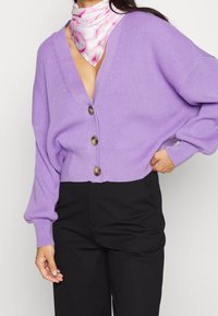 Lavendel gebreide cardigan met een diepe V-hals en vijf grote bruine knopen. De mouwen zijn wijd en bol, met een gladde textuur.