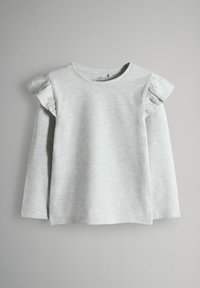 Ljusgrå långärmad T-shirt med volangdetaljer på axlarna. Mjukt, texturerat tyg med en klassisk rund hals och rak nederkant.