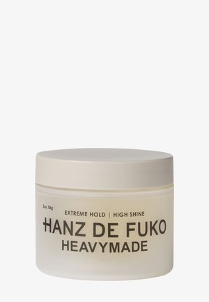Rund beige beholder med Hanz de Fuko Heavymade hårprodukt med etiket der angiver ekstrem hold og høj glans, 2 ounce.