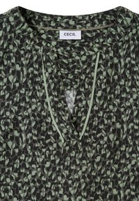 Green and black abstract leopard print blouse with a split V-neck trimmed with narrow green piping and a white "CECIL" label inside the collar.