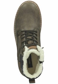 Botín de cuero marrón con forro de piel sintética blanca, cordones negros y detalles marrones. Presenta una puntera redonda y costuras en blanco.