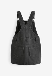 Schwarzes Denim-Latzkleid mit verstellbaren Trägern, strukturierter Form und zwei Rückentaschen. Hergestellt aus robustem Baumwollstoff mit glatter Textur.