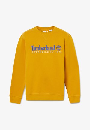 Sudadera amarilla con cuello redondo, puños y dobladillo acanalados, que presenta el logo azul de "Timberland" y el texto "Establecido en 1973".