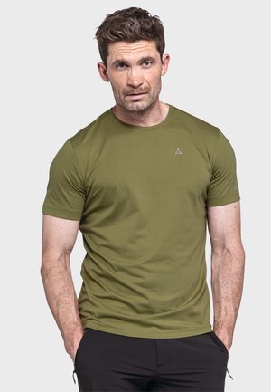 Grünes T-Shirt mit kurzen Ärmeln aus weichem Stoff, mit rundem Halsausschnitt und kleinem Logo auf der Brust. Getragen mit schwarzen Hosen.