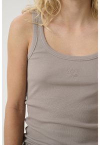 Top a canottiera grigia a coste con scollatura a girocollo e un piccolo logo sul davanti, che presenta un design aderente e una texture morbida.