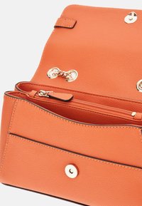 Borsa a mano in pelle arancione con superficie texture, dotata di un scomparto con zip e dettagli in hardware dorato.