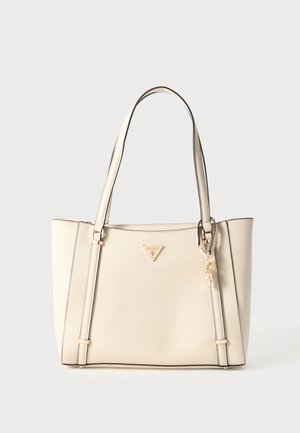 Beige Tragetasche aus synthetischem Material, mit zwei Griffen, einem dreieckigen Logo und einem dekorativen Anhänger. Flache rechteckige Form und glatte Textur.