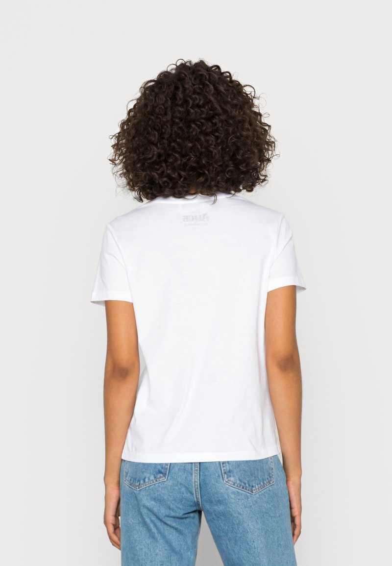 Valkoinen puuvillapaita, jossa on lyhyet hihat, pyöreä kaula-aukko ja hieman väljä istuvuus. Pieni brändäys näkyy yläselässä.