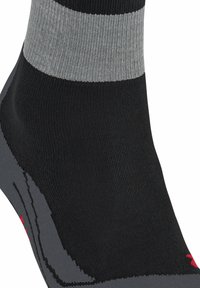 Calzini neri e grigi con texture a coste, caratterizzati da una striscia orizzontale grigia vicino alla parte superiore e un logo rosso sulla suola.