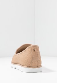 Scarpa beige slip-on con un motivo testurizzato in pelle di serpente, retro arrotondato, dettaglio di branding sottile e suola in gomma bianca. Fodera interna liscia.