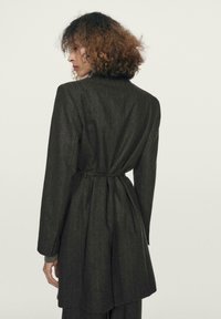 Mørkegrå, tøjstribede blazer med lange ærmer, bælte i taljen og skræddersyet design, med en glat tekstur og struktureret silhuet.