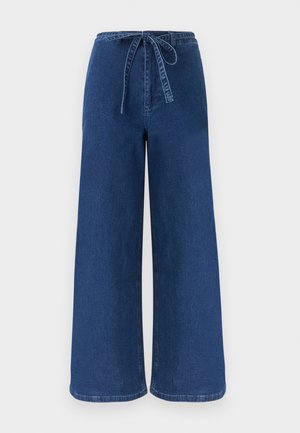 Φαρδιά μπλε τζιν παντελόνια με ψηλή μέση και υφασμάτινη ζώνη δεμένη φιόγκος μπροστά.