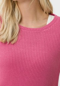 Maglione rosa a maglia strutturata con scollo rotondo e maniche corte. Il tessuto presenta un motivo a coste, che ne sottolinea il design traspirante.