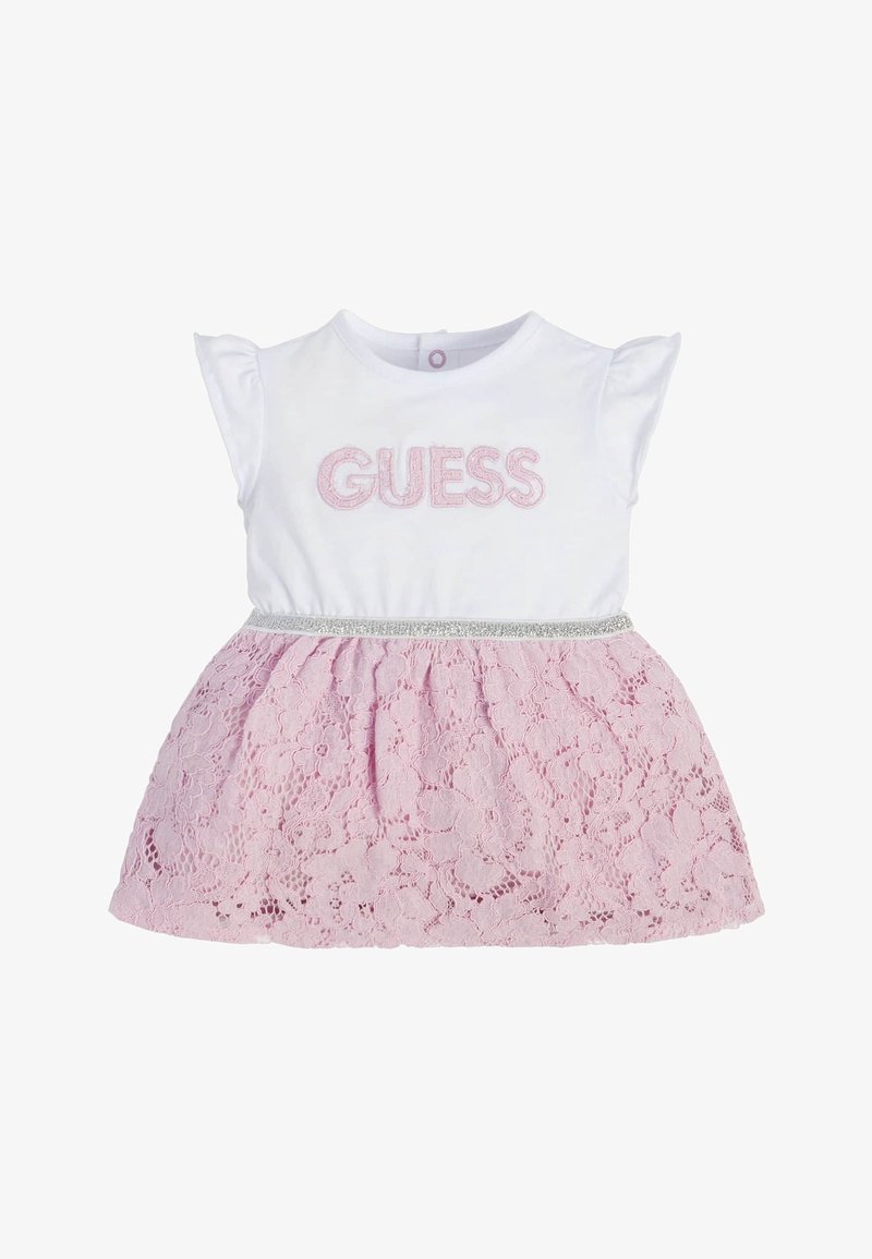 Robe blanche pour bébé avec manches courtes, jupe en dentelle rose, ceinture argentée, et "GUESS" brodé en rose sur la poitrine.