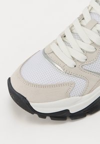 Sneaker leggera con tomaia in mesh traspirante, dettagli in suede beige, lacci bianchi e suola in gomma nera testurizzata per una migliore aderenza.