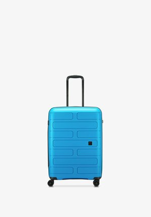 Maleta dura azul con una superficie texturizada, forma rectangular, mango retráctil y cuatro ruedas para movilidad.